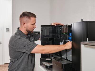 Servicetechniker öffnet und wartet einen professionellen Kaffeevollautomaten
